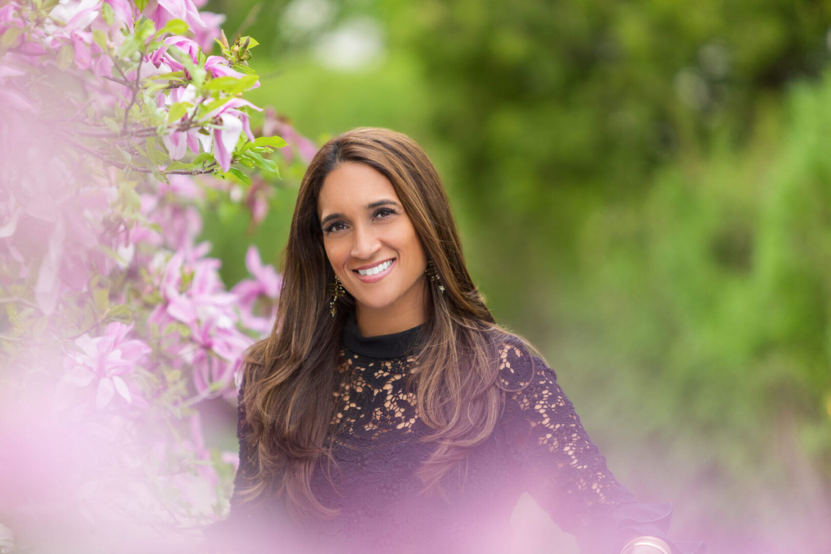 A woman in black shirt near purple flowers.